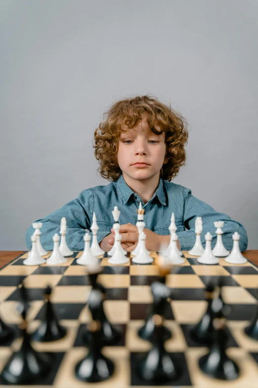 a young boy sitting at a table playing chess, an album cover, pexels contest winner, confident looking, child hybrid, gif, thumbnail