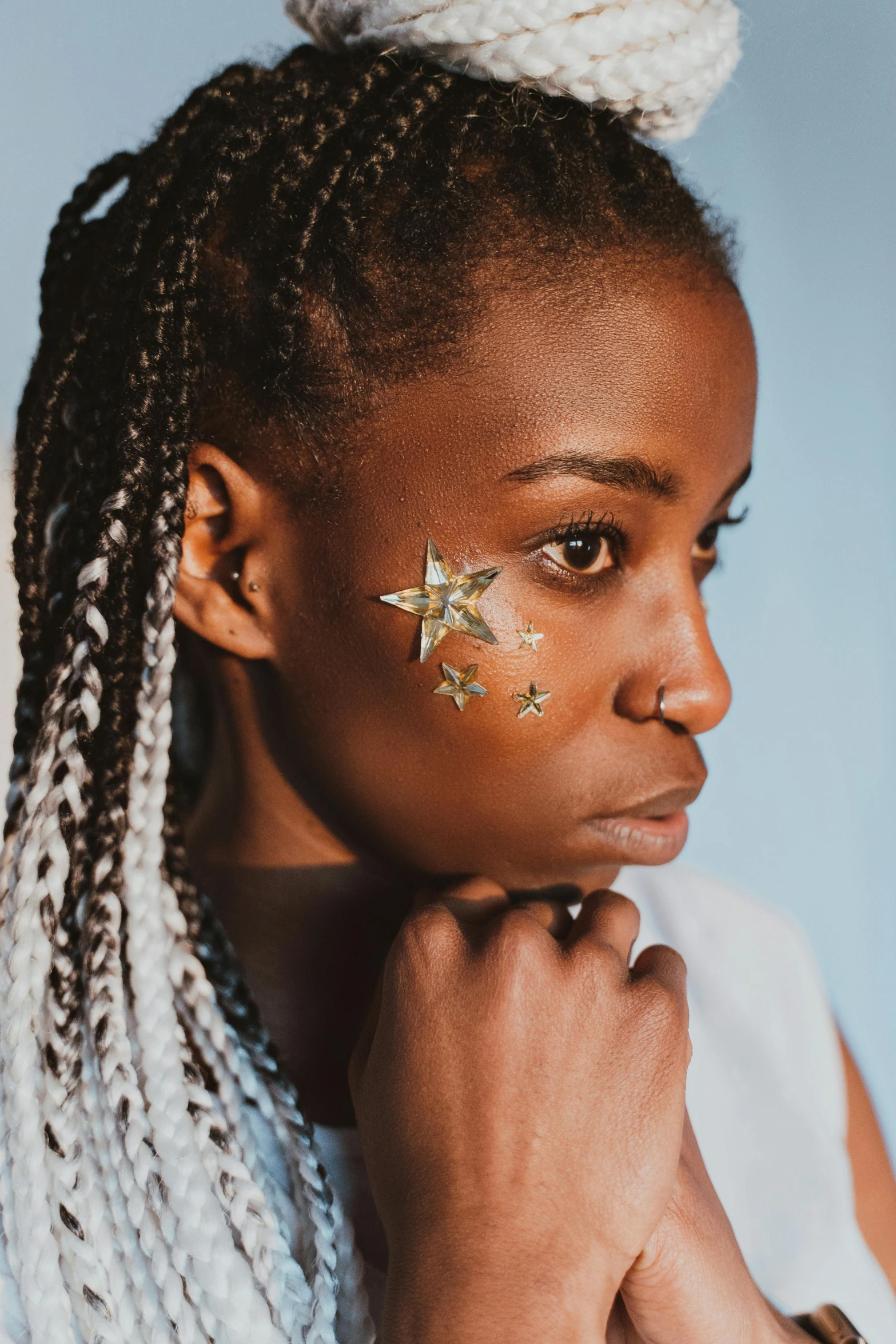 a woman with a star painted on her face, trending on pexels, afrofuturism, glitter sticker, side portrait rugged girl, girl silver ponytail hair, hand on cheek