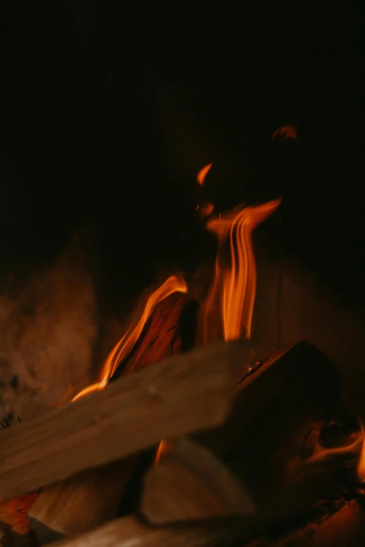a person holding a piece of wood in front of a fire, during the night, upclose, cinematic shot ar 9:16 -n 6 -g, fire texture
