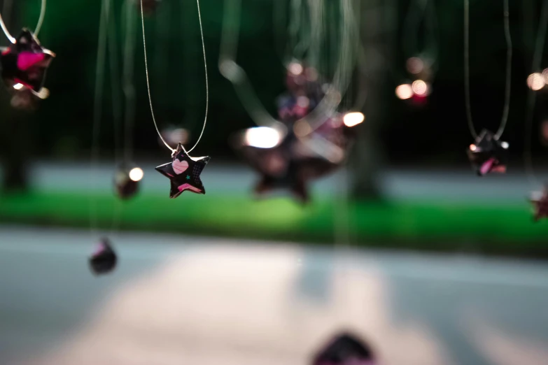 a bunch of stars hanging from a string, a tilt shift photo, by Julia Pishtar, pexels contest winner, silver and amethyst, pink, pendants, star inside