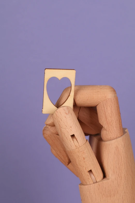 a wooden hand holding a piece of paper with a heart cut out of it, inspired by L. A. Ring, studio product shot, square shapes, from 8 k matte, laser cut