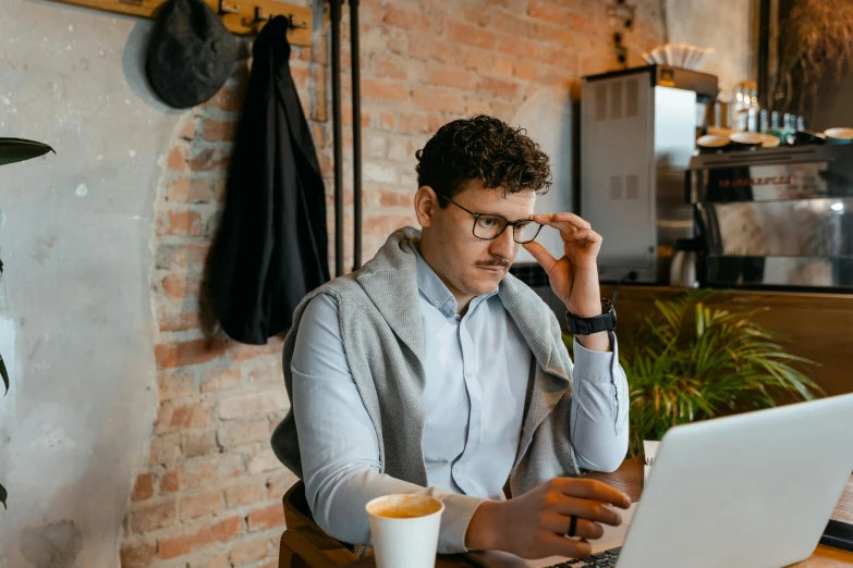 a man sitting at a table working on a laptop, trending on pexels, looking confused, realistic », small hipster coffee shop, background image