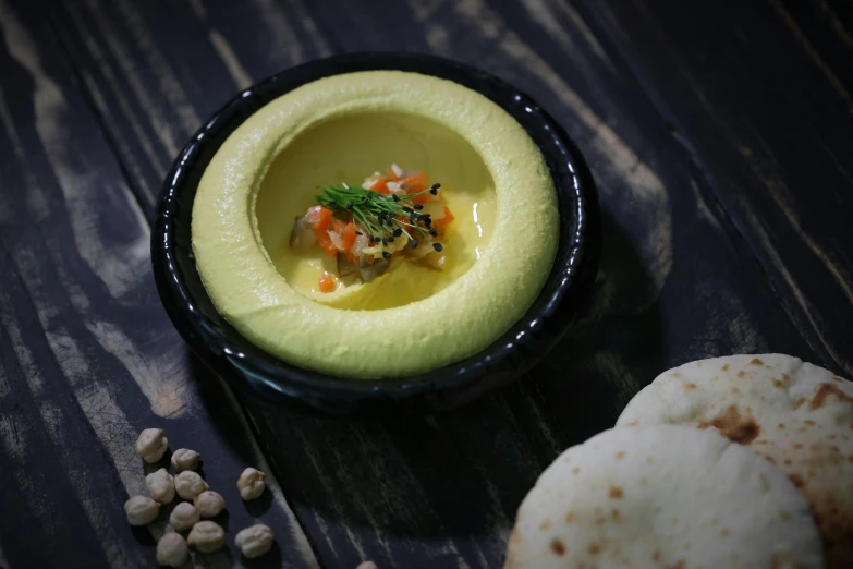 a close up of a bowl of food on a table, a pastel, inspired by Ceferí Olivé, unsplash, humus, avocado and cheddar, levitating agricultural sphere, middle eastern skin