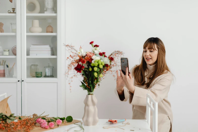 a woman taking a picture of a vase of flowers, by Julia Pishtar, low quality photo, various posed, fan favorite, portrait mode photo