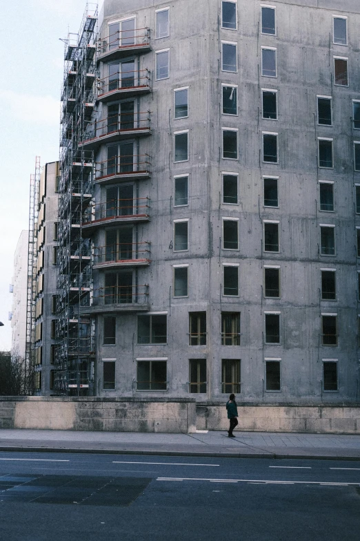 a man riding a skateboard down a street next to a tall building, inspired by Thomas Struth, brutalism, soviet apartment, photo taken on fujifilm superia, under construction, in paris