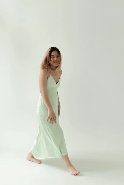 a woman in a green dress is walking, an album cover, inspired by Ina Wong, reddit, on a pale background, laughing, pastelwave, 5 0 0 px models