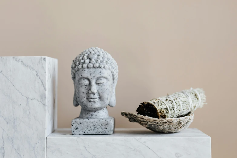 a statue sitting on top of a table next to a bowl, a marble sculpture, unsplash, minimalism, on a candle holder, south east asian with round face, detailed product image, frontal picture