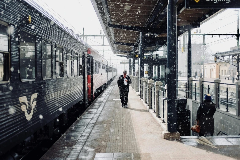 a couple of people standing on a platform next to a train, pexels contest winner, regionalism, snow flurry, 🚿🗝📝, thumbnail, terminals