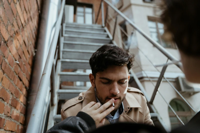 a man in a trench coat smoking a cigarette, trending on pexels, fire escapes, smoking a bowl of hash together, enes dirig, young adult male