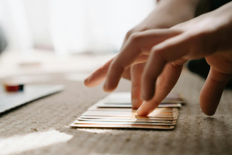 a close up of a person playing a game of domino, by Jessie Algie, trending on pexels, process art, pair of keycards on table, holding a wooden staff, warm coloured, slightly minimal