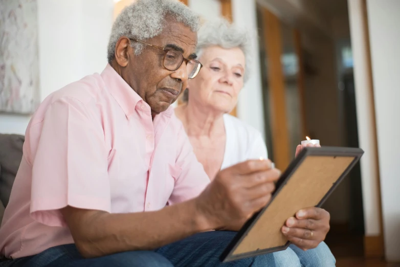 a man and a woman sitting on a couch looking at a tablet, a photo, nursing home, standing still, instagram post, pastel'