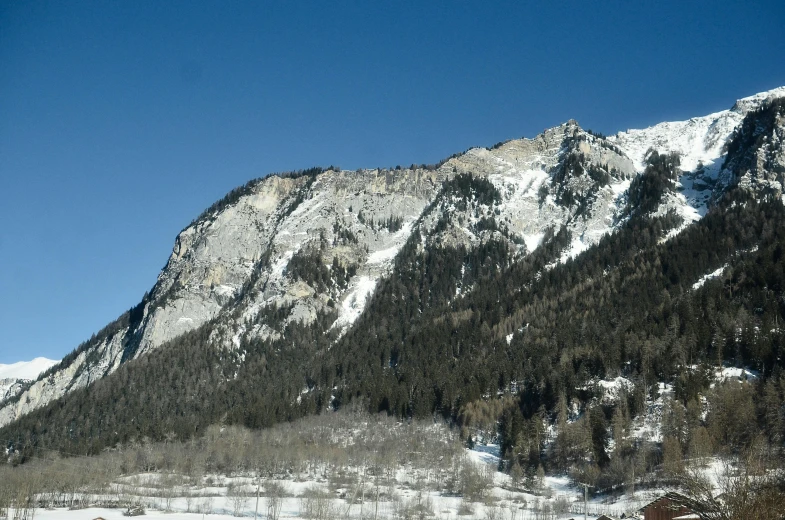 a group of people riding skis down a snow covered slope, trees and cliffs, blue clear skies, suzanne engelberg, landslides