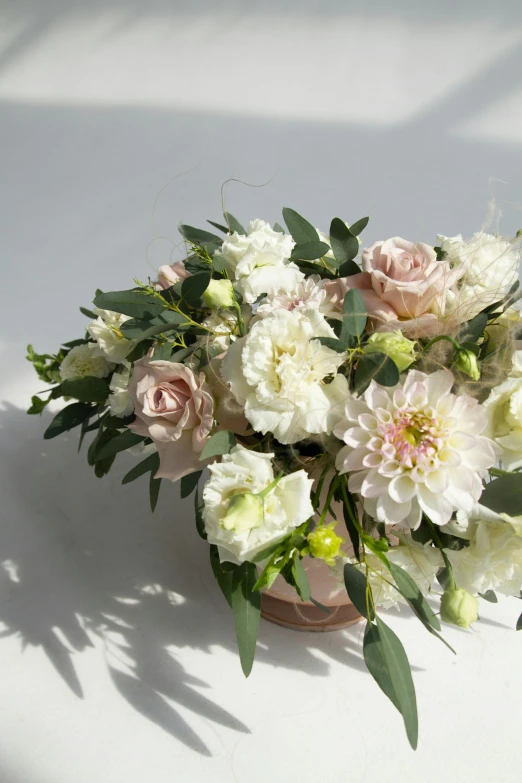 a bouquet of white and pink flowers on a table, inspired by Pierre-Joseph Redouté, romanticism, light cream and white colors, sun drenched, soft twirls curls and curves, front and center