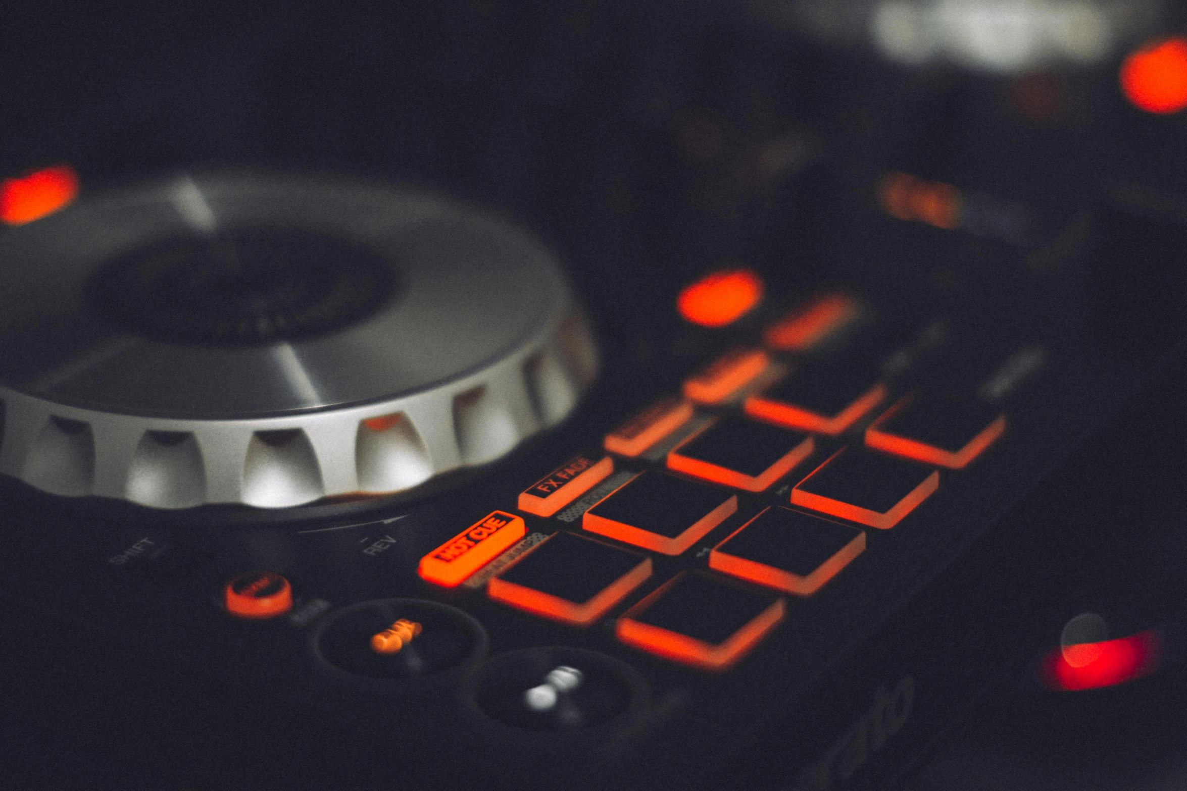 a dj controller sitting on top of a table, by Romain brook, trending on unsplash, black and orange, silver gold red details, led gaming, creating a soft