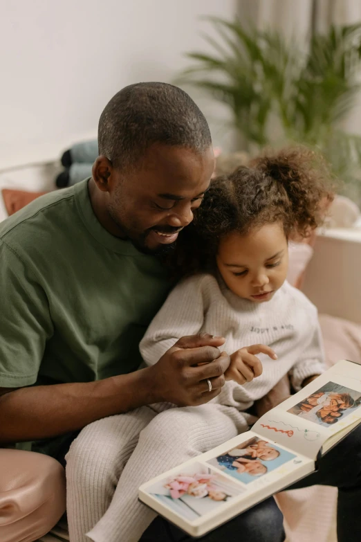 a man reading a book to a little girl, pexels contest winner, happening, black man, caring fatherly wide forehead, gif, medium shot of two characters