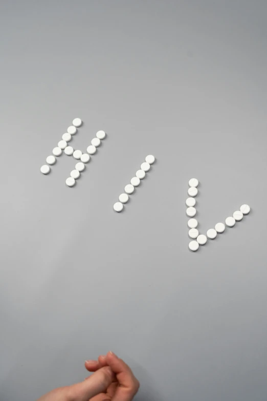 a person standing in front of a wall with pills on it, by Cerith Wyn Evans, visual art, helvetica, huhd, made out of shiny white metal, high angle close up shot
