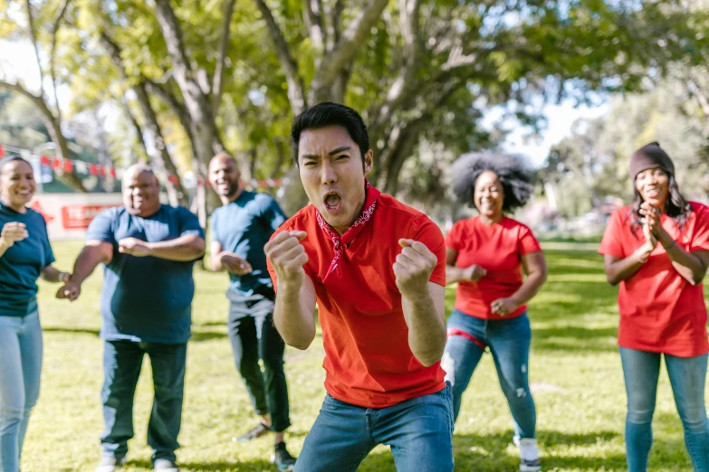 a group of people standing on top of a lush green field, fighting stance, red shirt, of a family standing in a park, performance