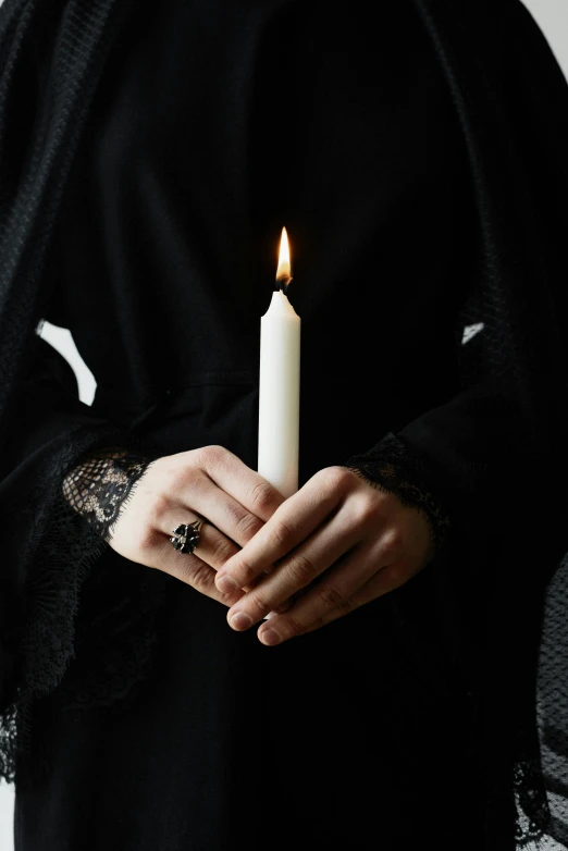 a woman in a black hijab holding a candle, an album cover, inspired by Marina Abramović, unsplash, bone jewelry, bone and ivory, mourning family, androgynous vampire