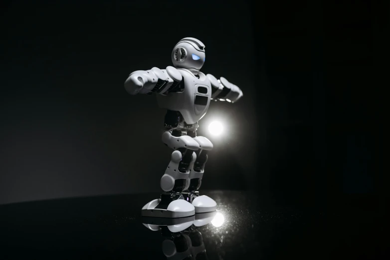 a close up of a toy robot on a table, a hologram, by jeonseok lee, pexels contest winner, standing in a dimly lit room, on a gray background, soft lighting 8k, exoskeletton