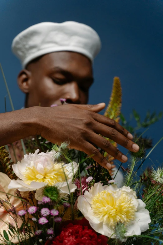 a man in a turban holding a bouquet of flowers, an album cover, inspired by Barthélemy Menn, trending on unsplash, delicate fingers, photography from vogue magazine, adut akech, fragrant plants