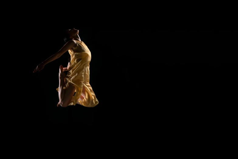 a woman in a yellow dress jumping in the air, by Maciej Kuciara, arabesque, on a black background, ignant, slide show, 4l