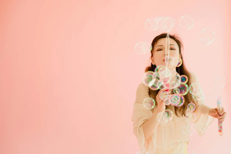 a woman blowing bubbles in front of a pink wall, an album cover, by Ayami Kojima, pexels contest winner, white background : 3, candy pastel, mingchen shen, sparkling