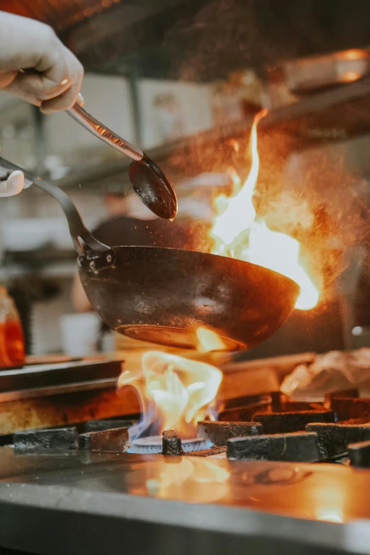 a person cooking food on a stove in a kitchen, golden embers flying, chefs table, thumbnail, forge