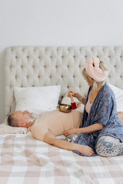 a woman laying on top of a bed next to a man, by Julia Pishtar, kundalini energy, bells, blonde, an oldman