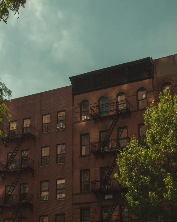 a tall brick building with lots of windows, trending on unsplash, harlem renaissance, lgbtq, trees outside, background image, dimly lit