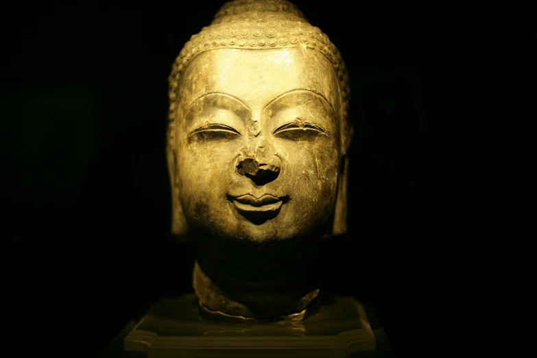 a close up of a statue of a person's face, dharma artifacts, museum lighting, in front of a black background, delightful surroundings