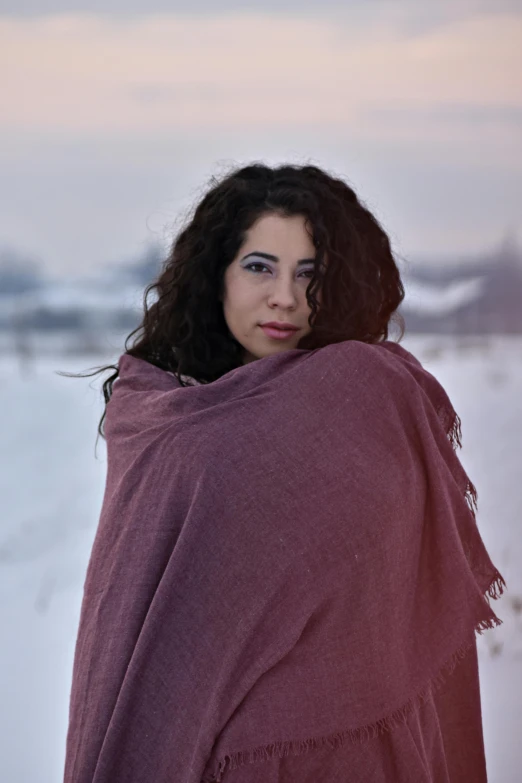 a woman wrapped in a blanket standing in the snow, an album cover, pexels contest winner, renaissance, young middle eastern woman, color photograph portrait 4k, casual pose, ukrainian