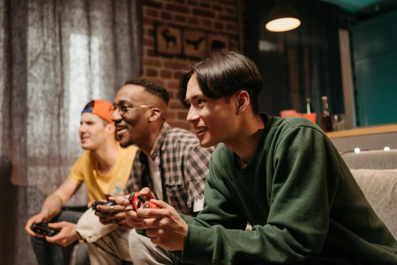 a group of men sitting on top of a couch playing a video game, trending on pexels, realism, profile picture 1024px, people sitting at tables, mix of ethnicities and genders, slightly smiling