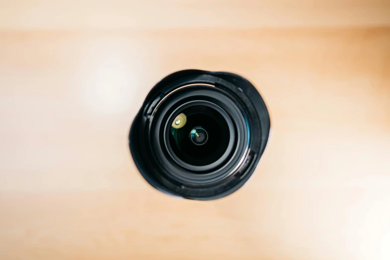 a camera lens sitting on top of a wooden table, unsplash, everything enclosed in a circle, camera looking down into the maw, looking up at camera, wide shot photograph