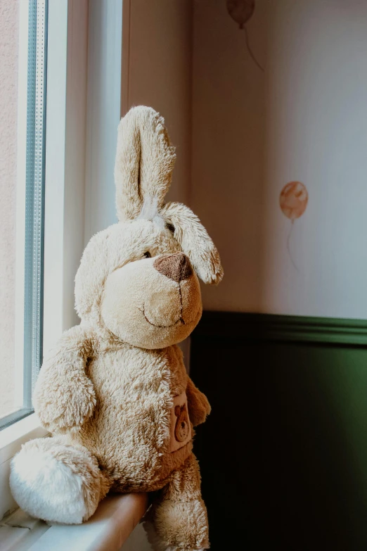 a teddy bear sitting on a window sill, with long floppy rabbit ears, soft internal light, bashful, toddler