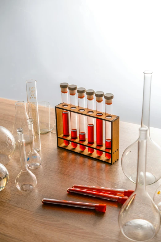 a group of glassware sitting on top of a wooden table, test tubes, product image, brown, scene