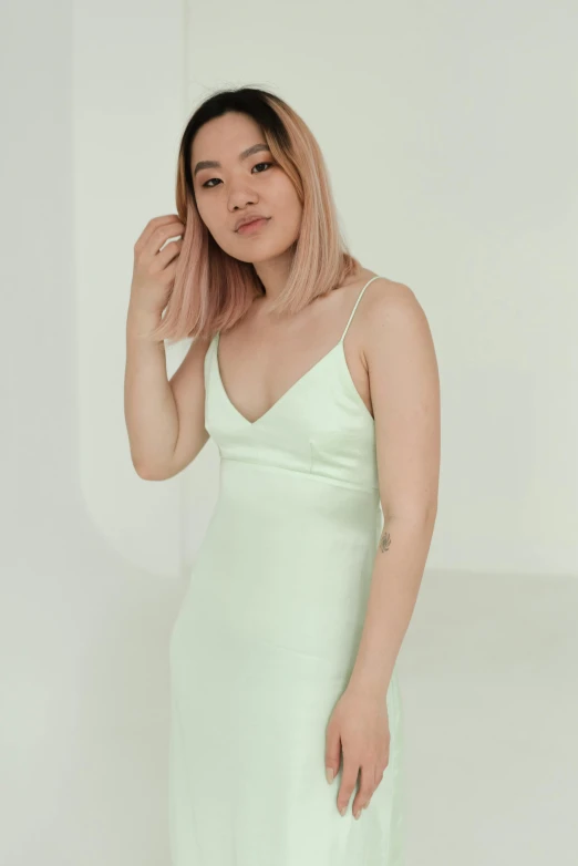 a woman in a green dress posing for a picture, inspired by Elsa Bleda, reddit, wearing white camisole, wenfei ye, white background, pastel colours overlap
