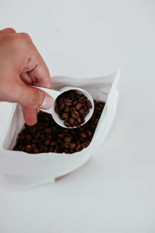 a person scooping coffee beans out of a bag, an album cover, by Andries Stock, unsplash, 15081959 21121991 01012000 4k, paper cup, thumbnail, dynamic closeup