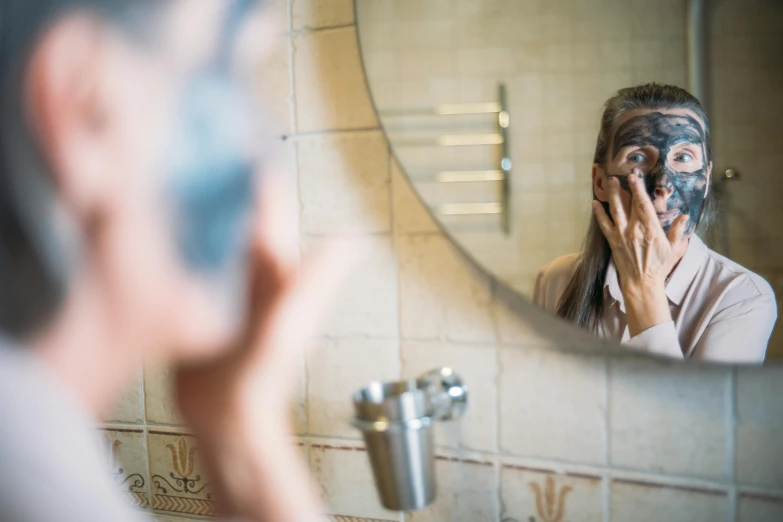 a man shaving his face in front of a mirror, a picture, by Julia Pishtar, older woman, holding his hands up to his face, wearing eye shadow, photo of a woman