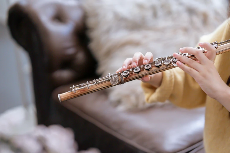 a close up of a person playing a flute, inspired by Edward George Handel Lucas, trending on pexels, arabesque, rose gold, mini model, sitting on a sofa, zoomed out shot