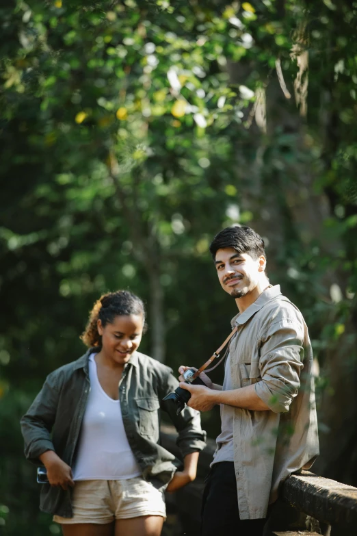 a man standing next to a woman on a bridge, in a jungle environment, holding a camera, profile pic, tan