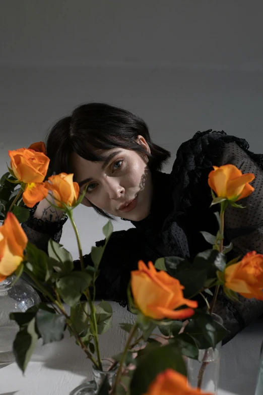 a woman leaning over a vase filled with orange roses, an album cover, inspired by Winona Nelson, romanticism, krysten ritter, profile image, low quality photo, made of flowers