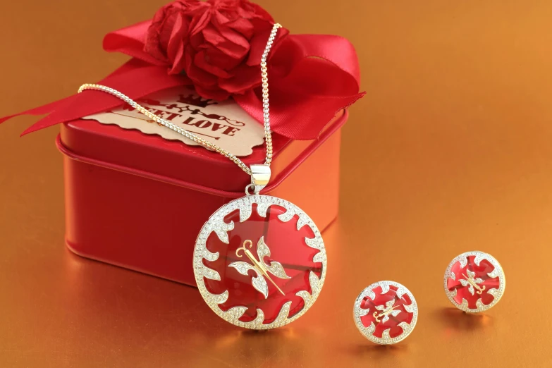 a red gift box sitting on top of a table, wearing several pendants, butterfly jewelry, 3 - piece, high quality product image”