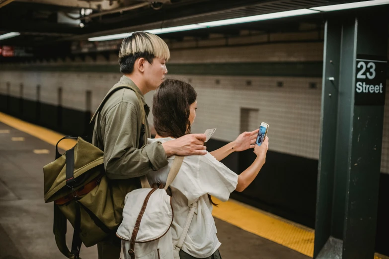 a man and woman standing next to each other at a train station, by Carey Morris, pexels contest winner, hold up smartphone, japanese, avatar image, among us