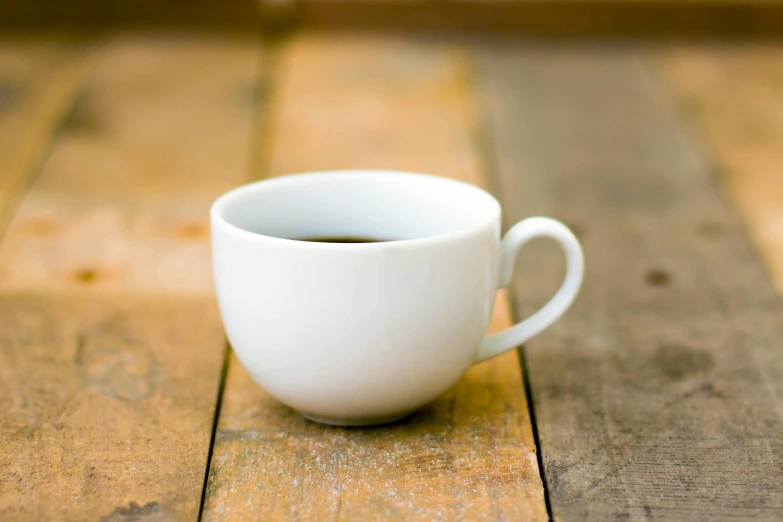 a cup of coffee sitting on top of a wooden table, by John Henderson, unsplash, organic ceramic white, close up front view, hero shot, small