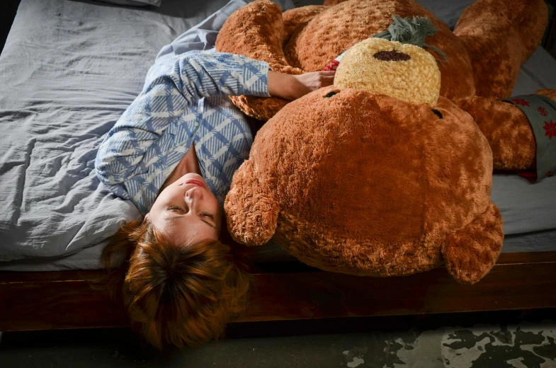 a woman laying on top of a bed next to a giant teddy bear, process art, brown, professionally assembled, thick lining, detailed photograph