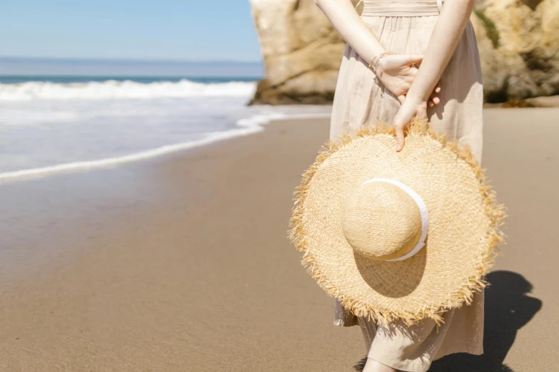 a woman standing on a beach holding a straw hat, by Gawen Hamilton, unsplash, renaissance, in a sunny day, round-cropped, ad image, less detailing