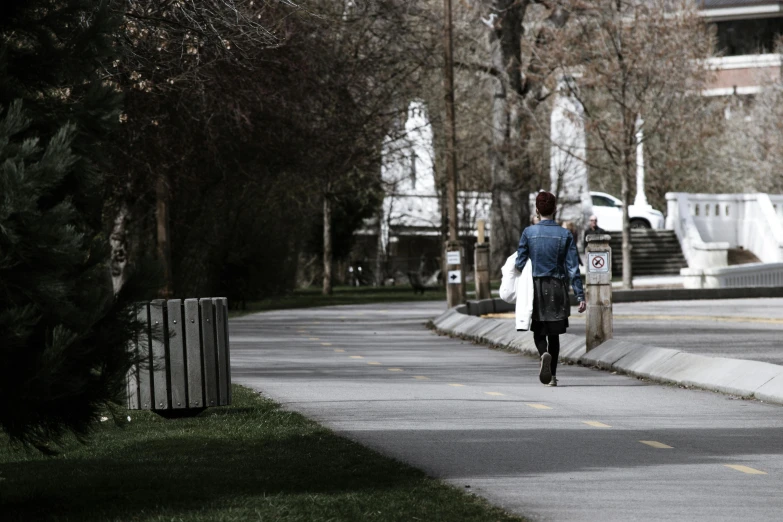 a person riding a bike down a street, walking at the park, bags on ground, facing away from the camera, in a park