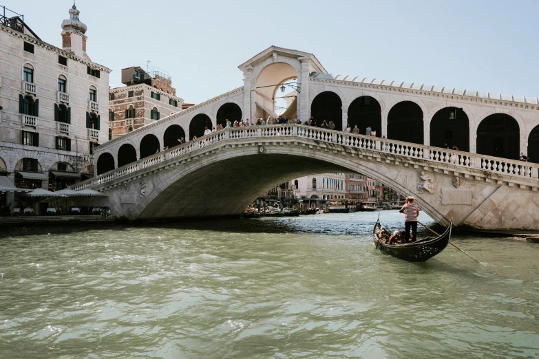 a gondola going under a bridge in venice, by Canaletto, pexels contest winner, renaissance, slightly tanned, white sweeping arches, over the shoulder, summer weather