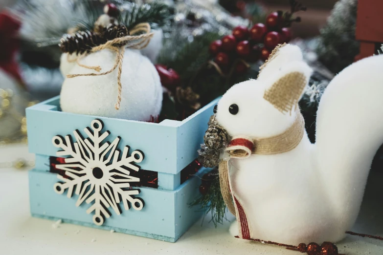 a white squirrel sitting in a blue box next to a snowflake, pexels contest winner, folk art, stuffed toy, wooden decoration, white, felt