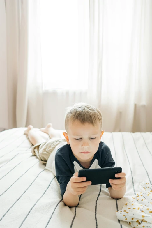 a young boy laying on a bed using a cell phone, trending on pexels, among us video game, square, looking serious, v tuber